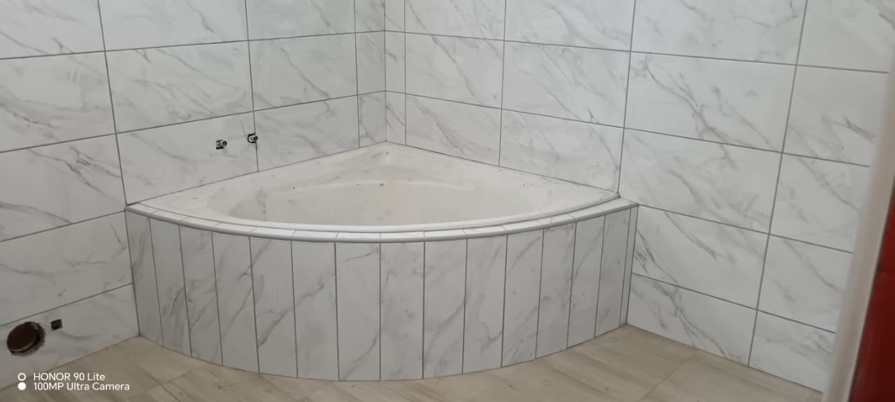 Tiled corner bathtub installation with wall-mounted taps