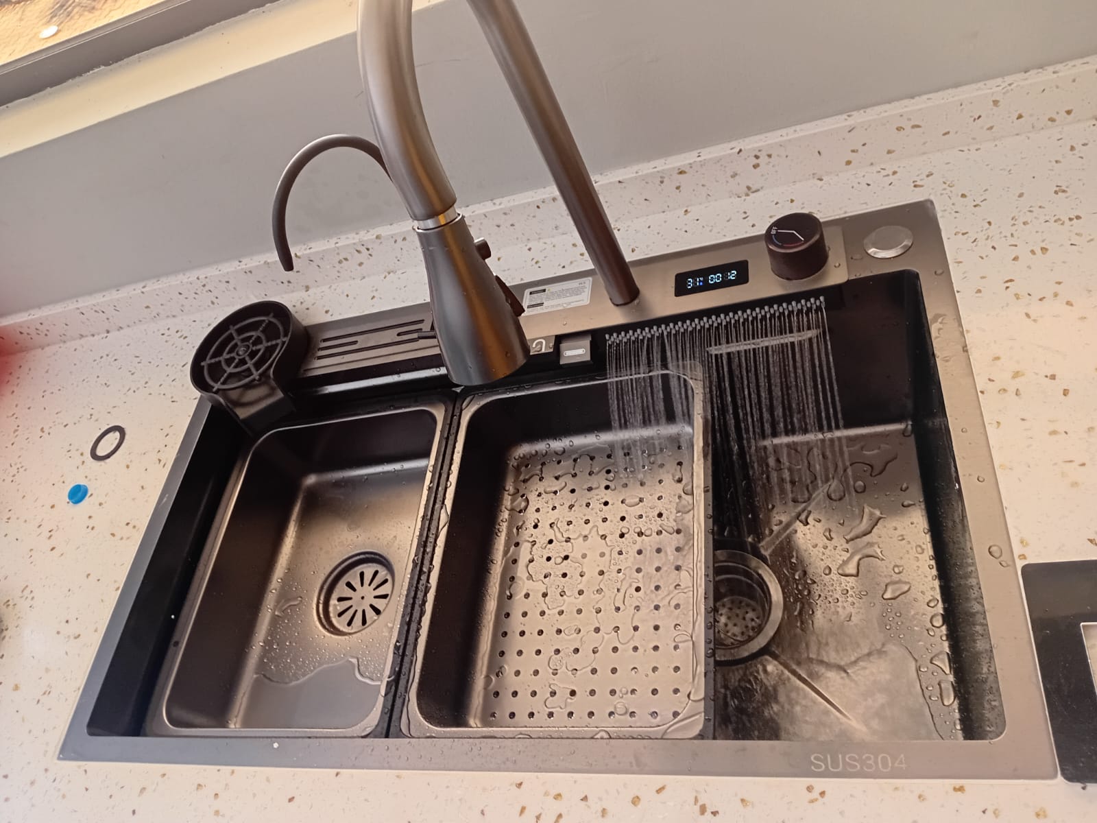 Double-basin kitchen sink with pull-out spray tap installed on a stone countertop