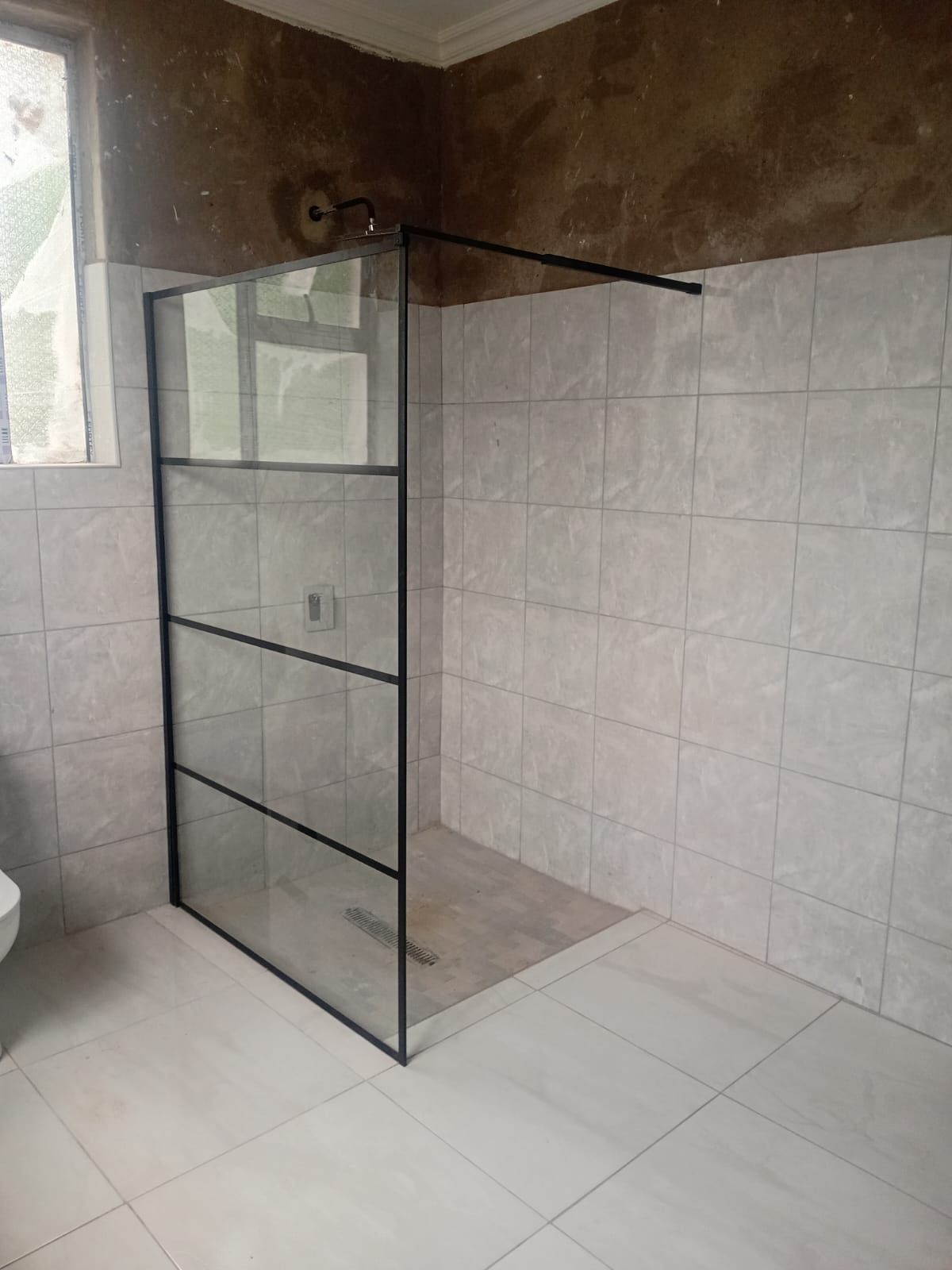 Frameless glass walk-in shower screen fitted in a tiled shower