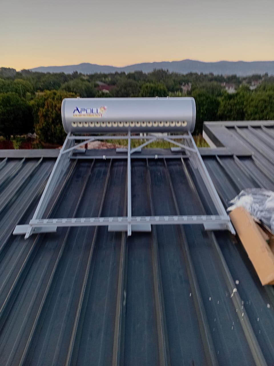 Solar geyser installed on a metal roof at sunset