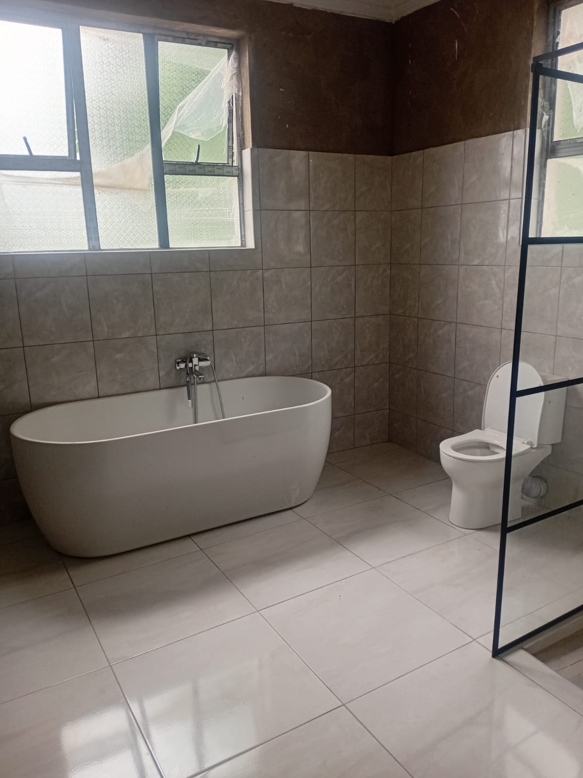Close-up of a wall-hung toilet with dual-flush plate in a tiled bathroom