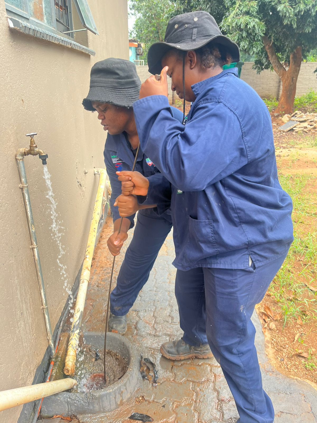 Pfano & Given Plumbing technicians using a drain rod to clear a blocked outdoor drain